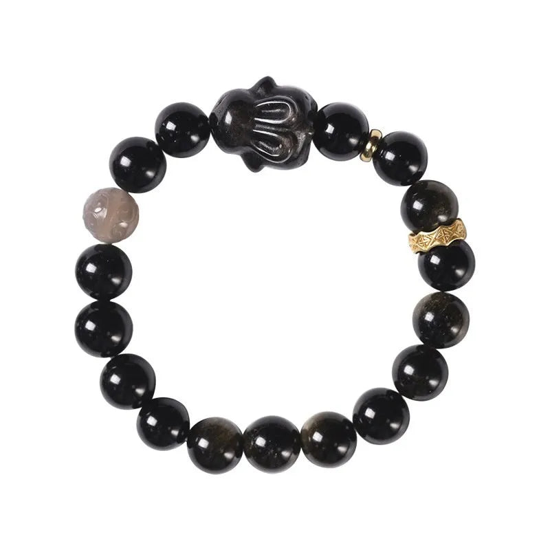 Close-up of a handmade lying rabbit obsidian bracelet in brass with grey agate beads.