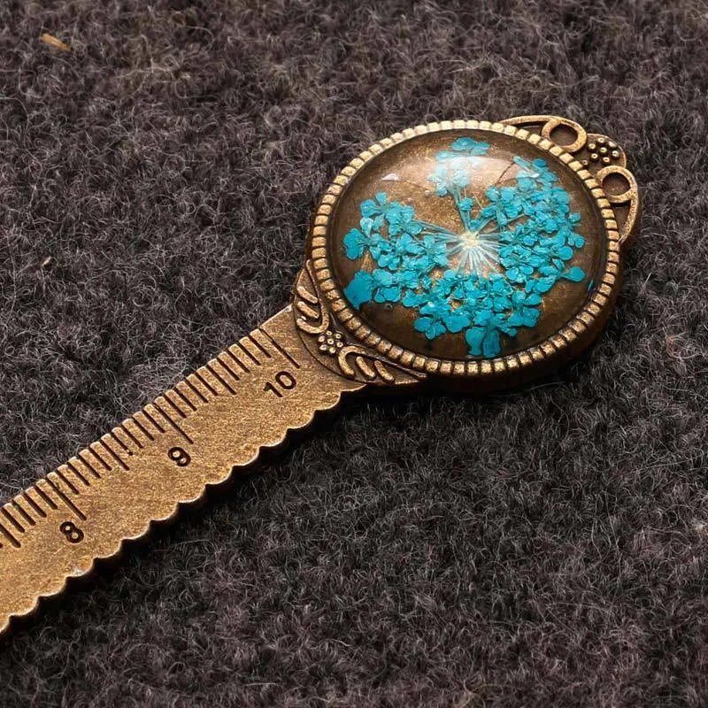 Handmade dried gypsophila, daffodil, and four-leaf clover bookmark on a book page.