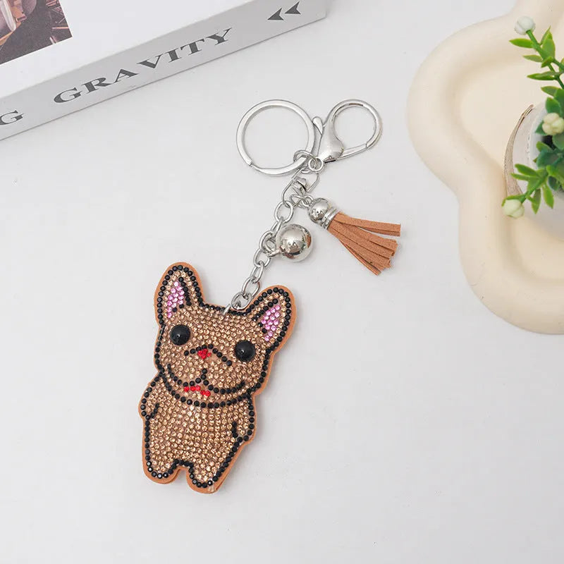Close-up of a caramel-coloured cartoon dog rhinestone keychain pendant on a keyring.