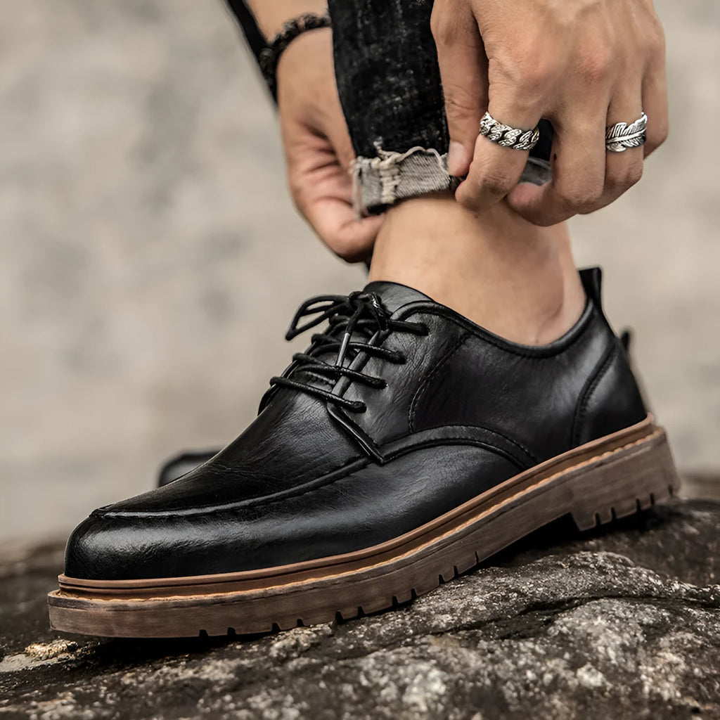 Black and brown round-toe casual leather shoes with visible stitching and flat rubber soles.