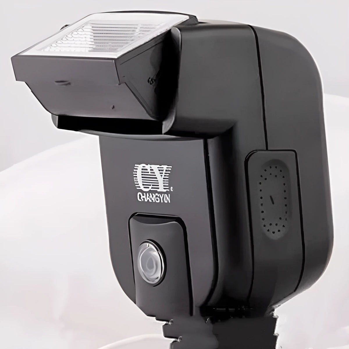Compact silver hot shoe camera flash with head tilted upwards, shown next to two AA batteries for scale.