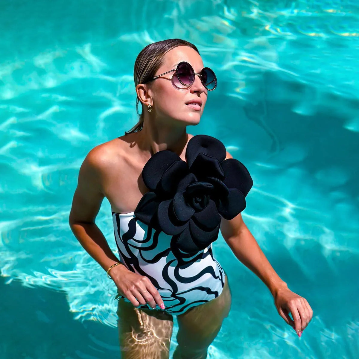 Women's black floral one-piece swimsuit with three-dimensional pattern on polyester fabric.
