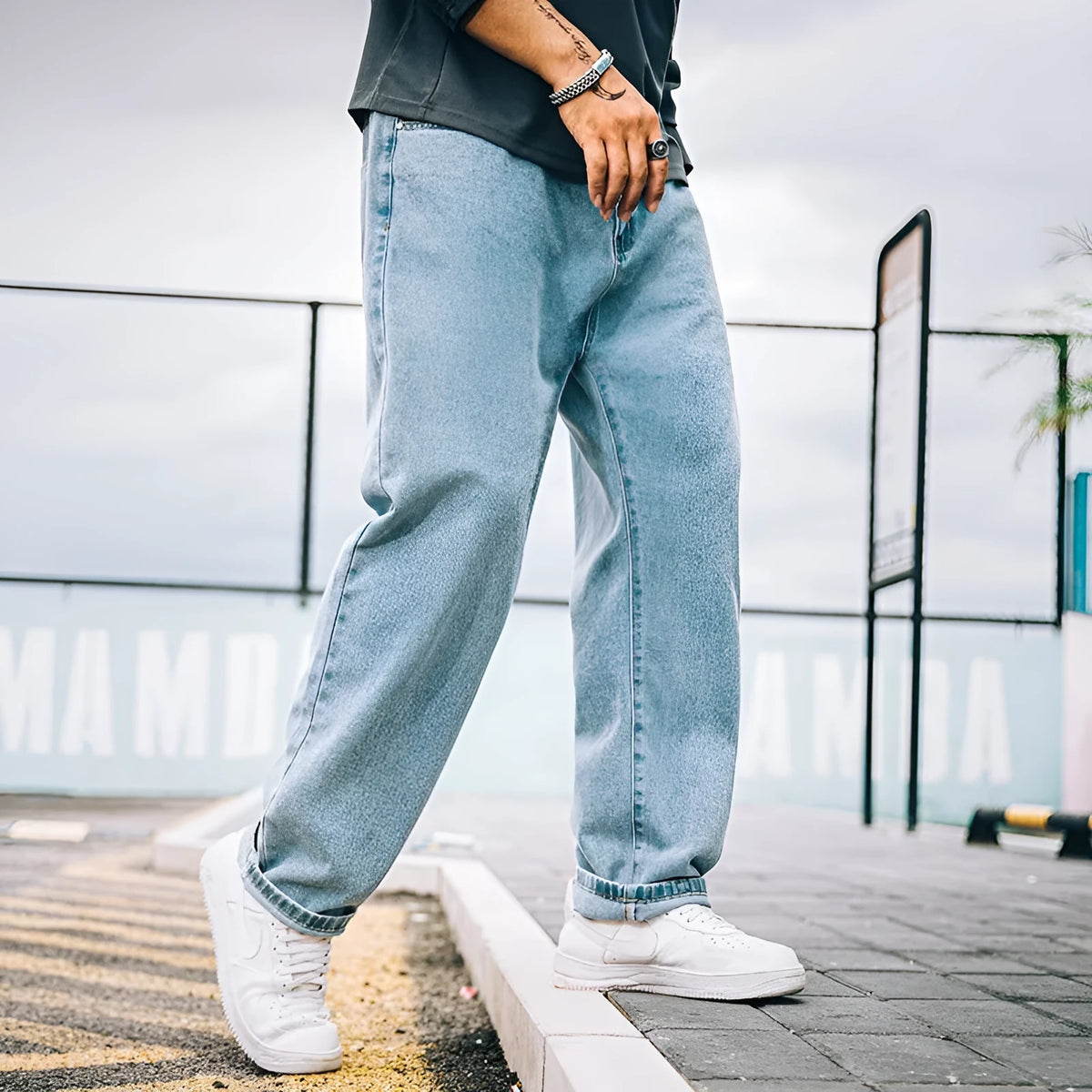 Men's loose straight blue jeans on hanger showing mid-waist design and straight leg cut