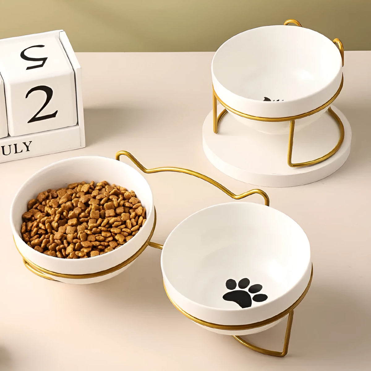 White ceramic cat bowl with cat paw print design sitting in a black iron frame stand