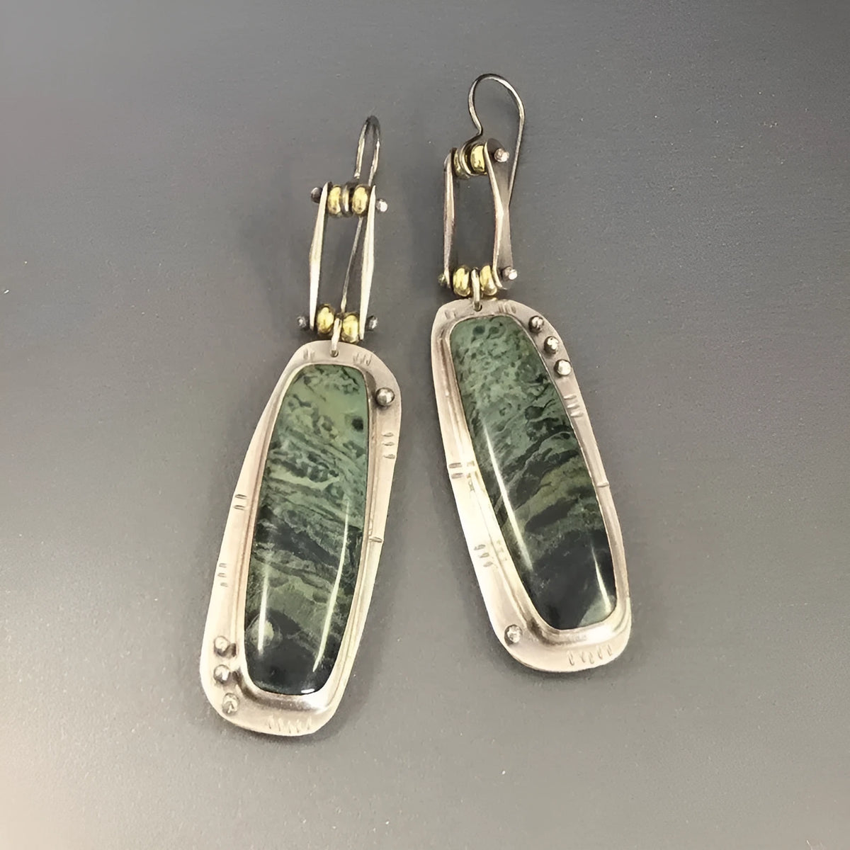 A pair of silver and grey geometric drop earrings with a marble stone pattern on a white background.