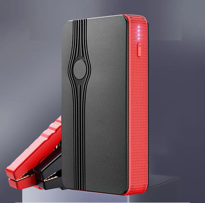 Red K4-E automobile emergency starting power supply unit with a data cable on a surface.