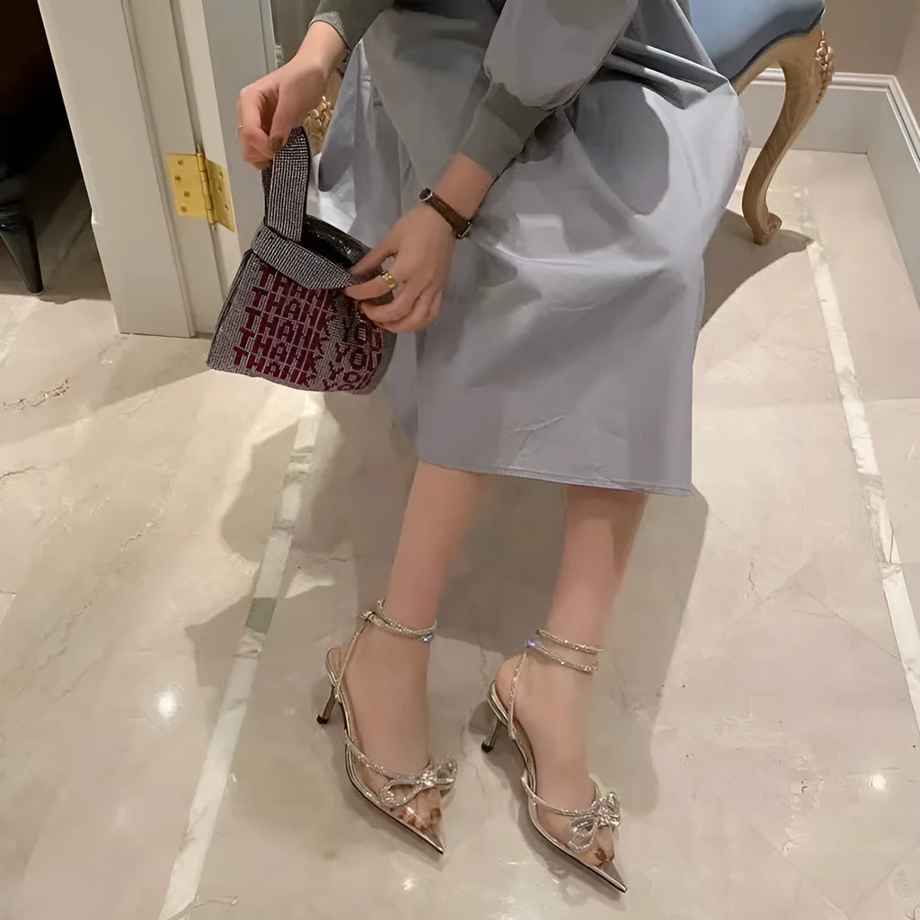Women's black stiletto heel sandals with a silk bandage wrap back and buckle fastening, showing pointed toe.