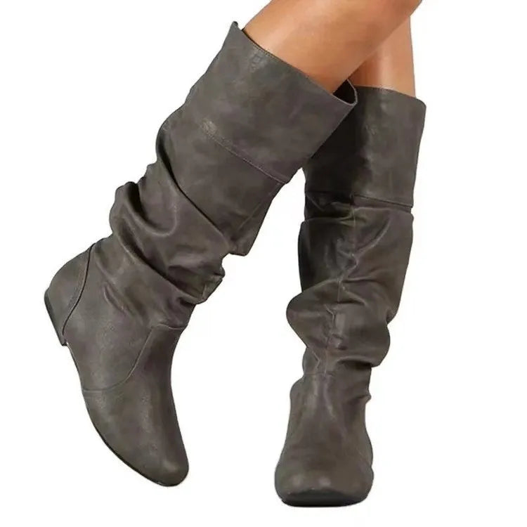 Women's flat heel slip-on boot in artificial PU with high cut and rubber sole.
