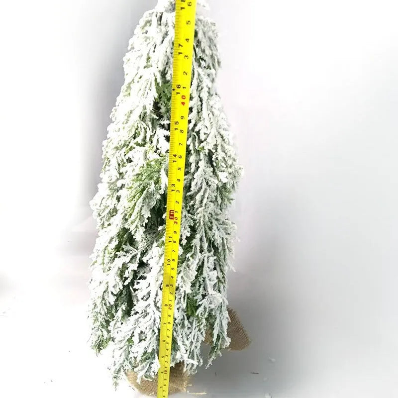 Small white artificial Christmas tree with built-in lights and snow sprayer decoration on desktop