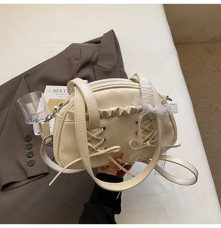 Women's milky white PU shoulder bag with bandage bow and stitching detail, showing internal phone pocket.