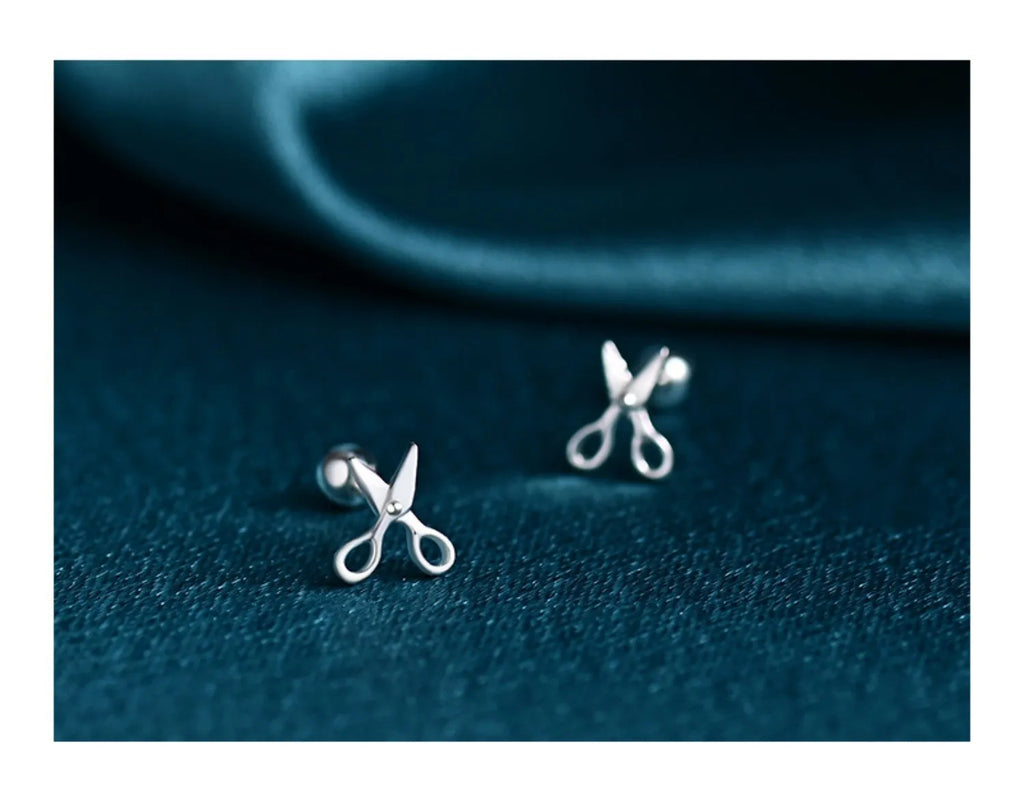 A pair of pure silver earrings with a miniature scissors design and screw-on backs.