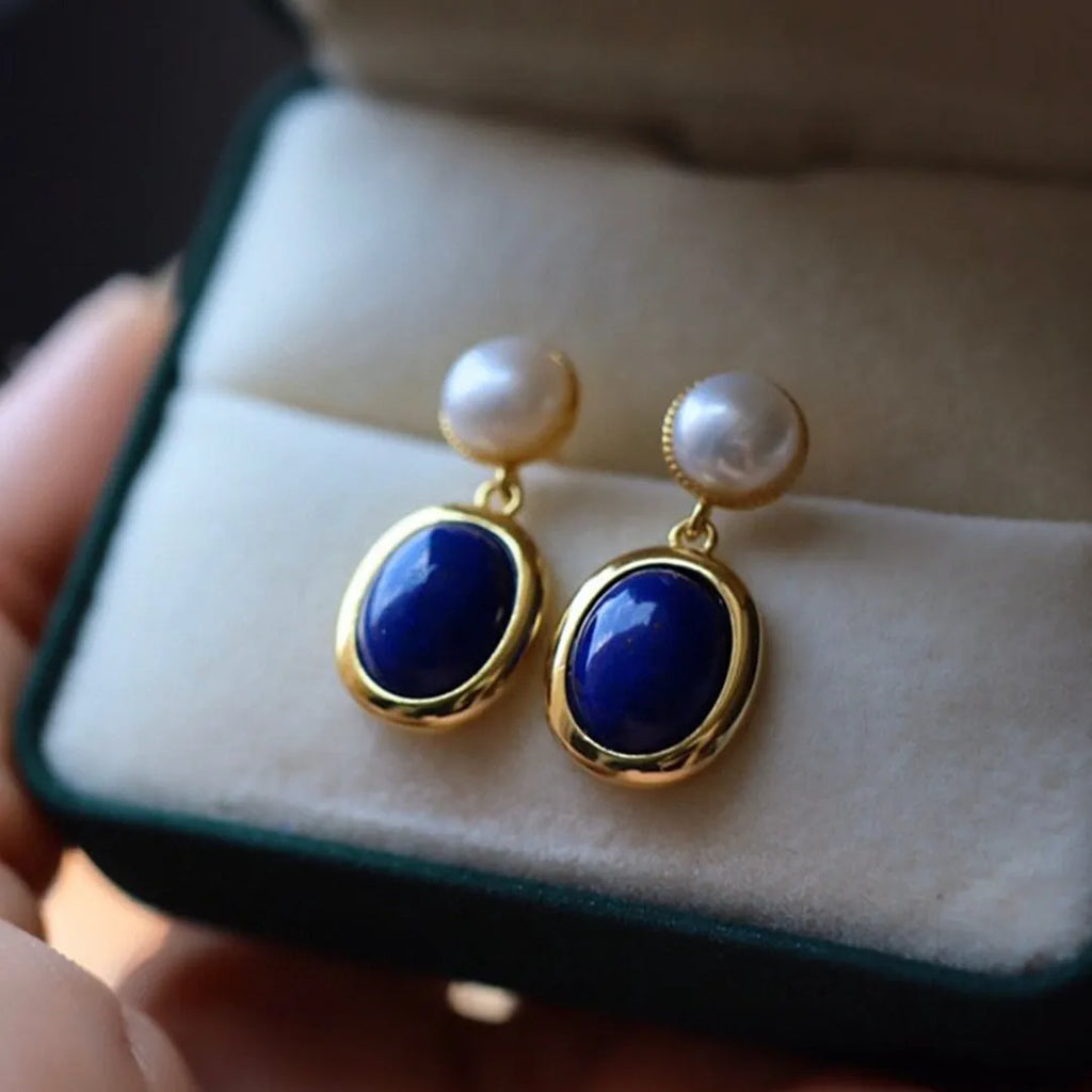 A pair of 925 sterling silver stud earrings with a deep blue lapis lazuli pearl and auspicious pattern details.