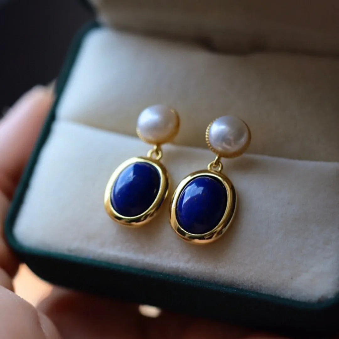 A pair of 925 sterling silver stud earrings with a deep blue lapis lazuli pearl and auspicious pattern details.