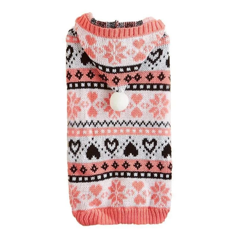 Pink knitted dog sweater with snowflake, heart, and camouflage stripe pattern on a small white dog.