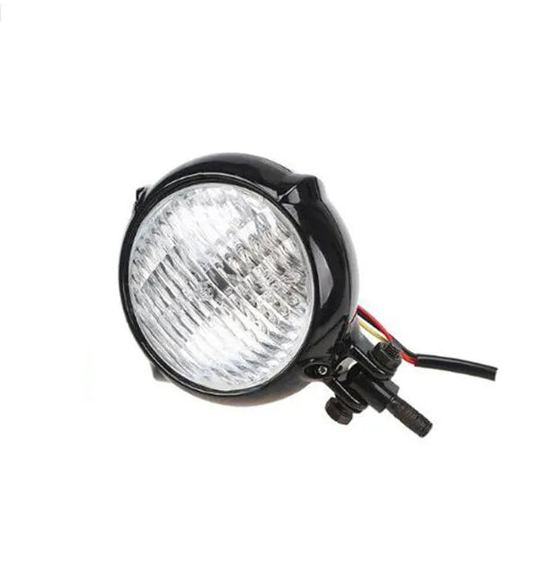 Harley-style motorcycle headlight in black cast aluminium with a circular glass lens.
