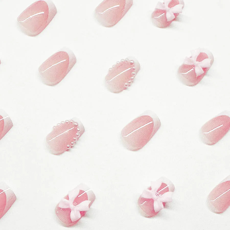 Short white French manicure false nails with decorative bow and tulip designs.