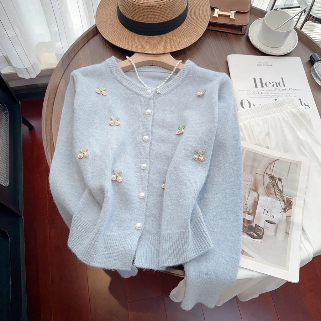 A pink cashmere blend ladies cardigan with beaded details, shown on a hanger.