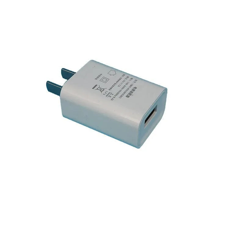 Thin white USB wall charger with CE and FCC markings showing universal voltage input and 5V 1A output