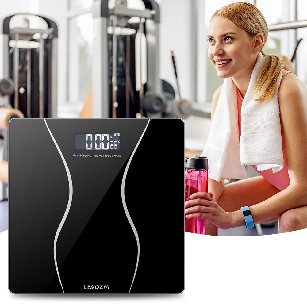 Black electronic personal body scale on a floor, showing digital display.