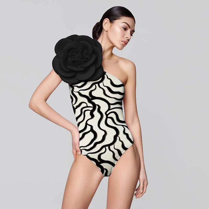 Women's black floral one-piece swimsuit with three-dimensional pattern on polyester fabric.