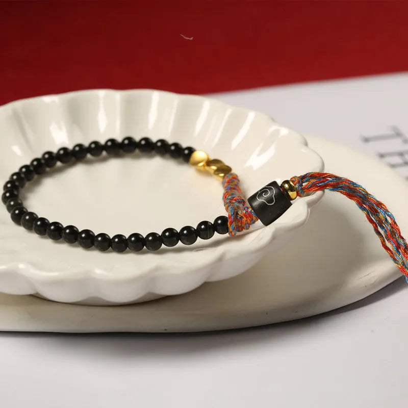 Slim obsidian-coloured hand-woven strap bracelet shown on a wrist.