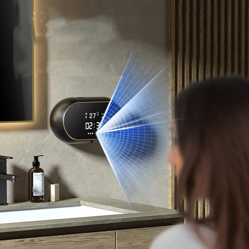 White automatic wall-mounted soap dispenser with USB cable on a bathroom wall