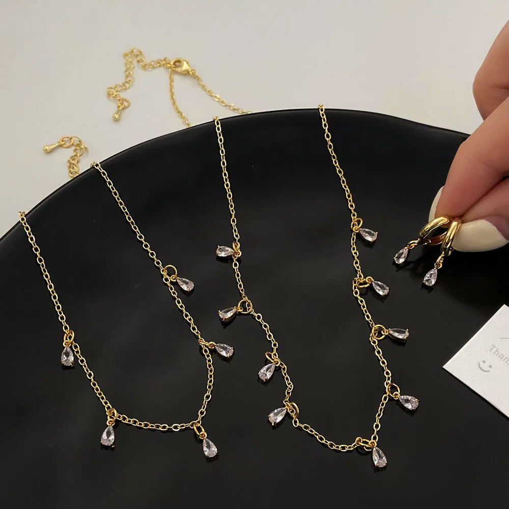 Women's zircon jewellery set showing geometric pendant necklace, matching earrings and coordinating anklet