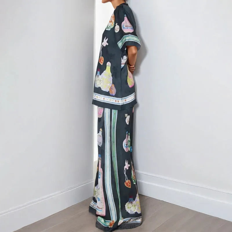 Black women's cardigan and pants set with cartoon animation pattern, laid flat.