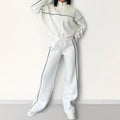 Casual two-piece suit set with a mock neck zip hoodie and striped trousers on a hanger.