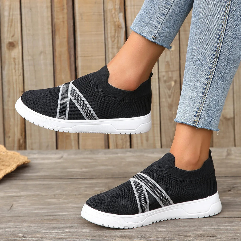 Women's black casual shoes with fabric mesh upper and flat rubber sole on neutral background