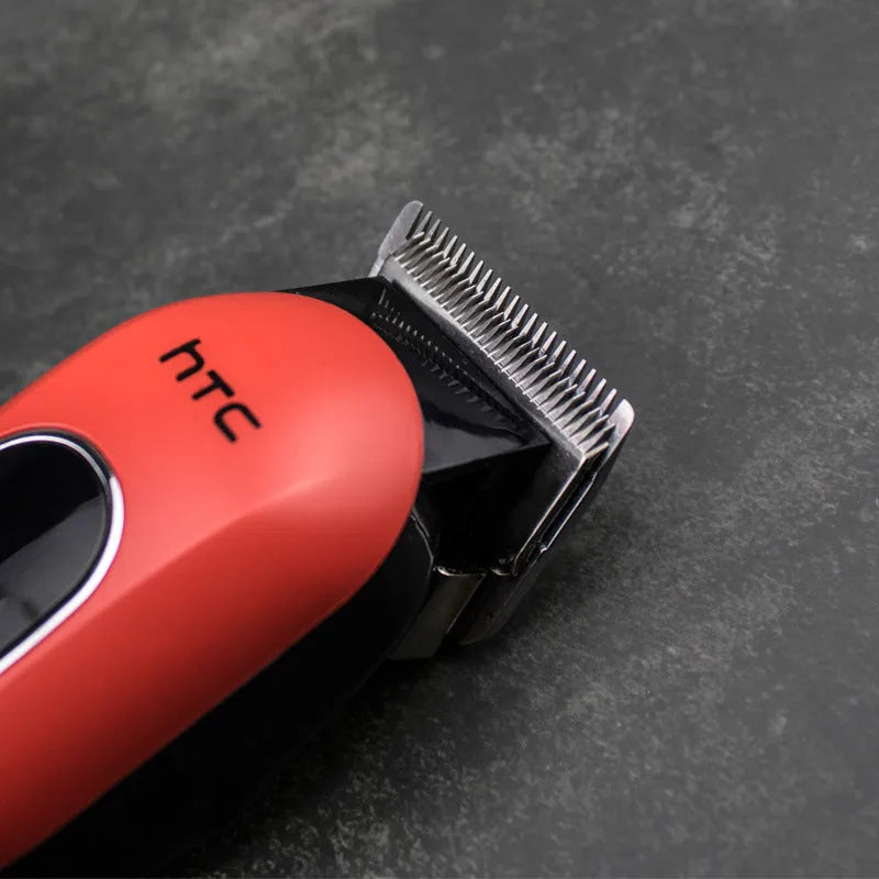 Red rechargeable hair clipper with four attachment combs, a charger, and grooming accessories on a white background.