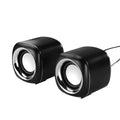 Compact black wired desktop computer speaker pair with 3.5mm plug next to a laptop.