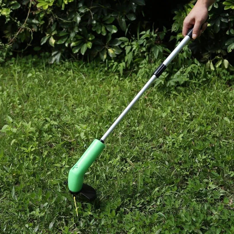 Cordless handheld lawn trimmer with extension pole and protective shield on a garden lawn.