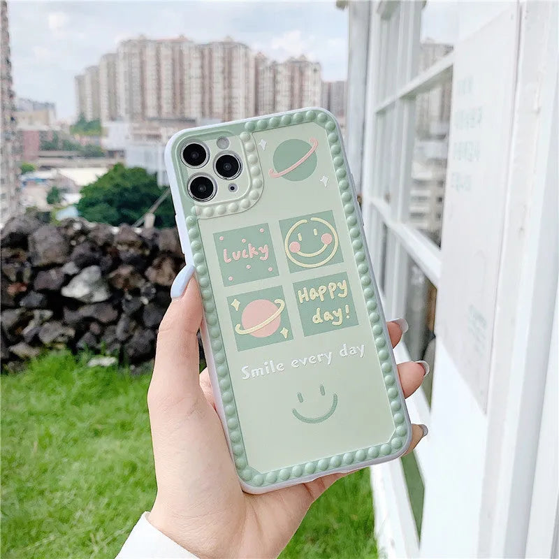Green TPU iPhone case with geometric smiley face design, shown in polka dot frame and square grid styles.