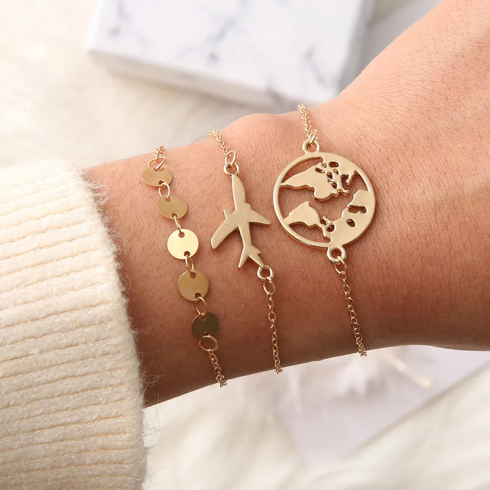 Three Bohemian-style bracelets with aircraft map and heart charms in gold electroplated finish