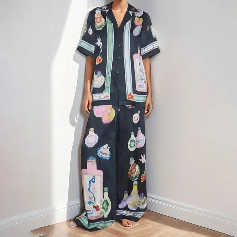 Black women's cardigan and pants set with cartoon animation pattern, laid flat.