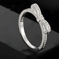 Silver couple's ring with a bow shape and sparkling zircon crystal rhinestones on a finger.