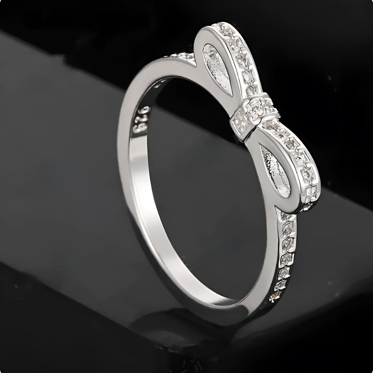 Silver couple's ring with a bow shape and sparkling zircon crystal rhinestones on a finger.