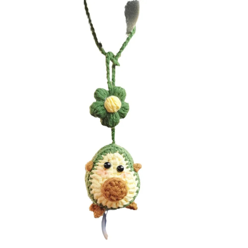 Handmade crocheted avocado-shaped car pendant with rainbow pattern, hanging.