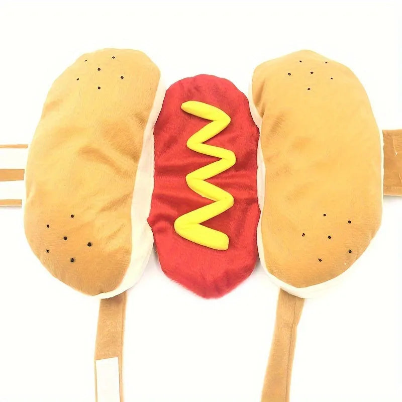 Small dog wearing a red and brown plush hot dog costume with bun and sausage design.