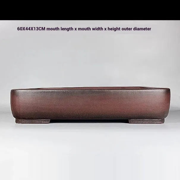 Handmade antique rectangular purple clay flower pot on a wooden surface.