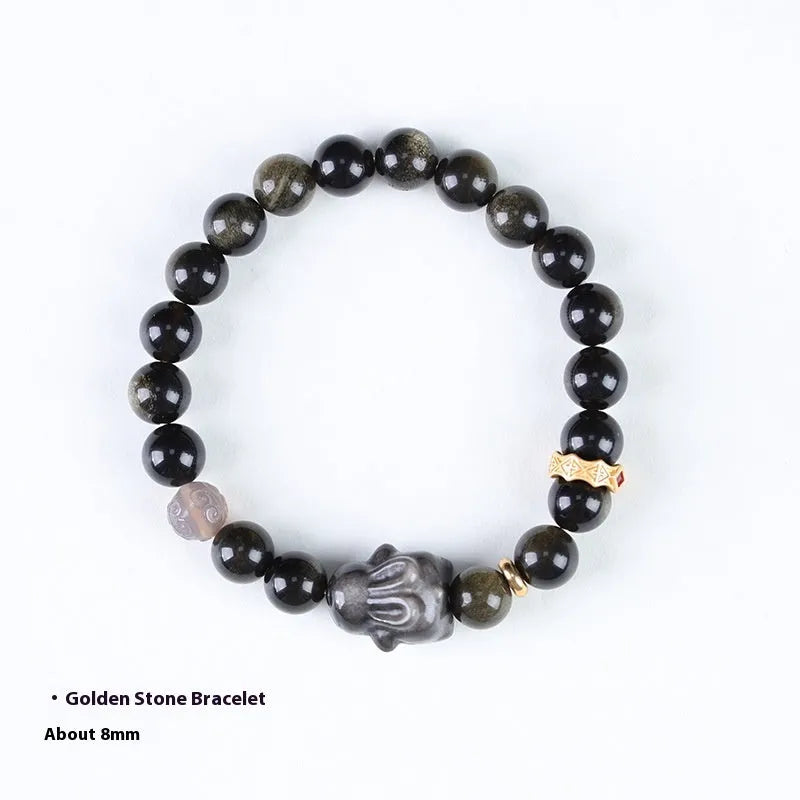 Close-up of a handmade lying rabbit obsidian bracelet in brass with grey agate beads.