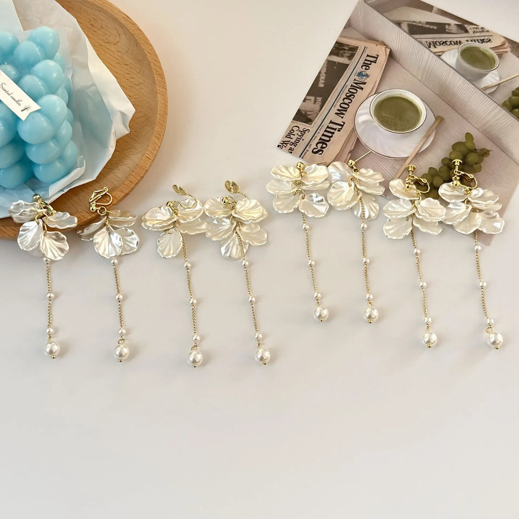 Women's acrylic fashion earrings with white shell and pearl tassel design on a silver-toned ear clip.