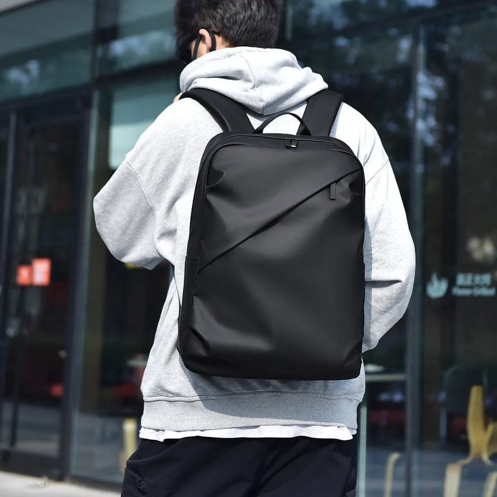 Large waterproof backpack in PU leather with sewing thread detailing, includes computer bag