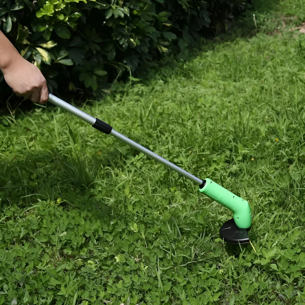 Cordless handheld lawn trimmer with extension pole and protective shield on a garden lawn.
