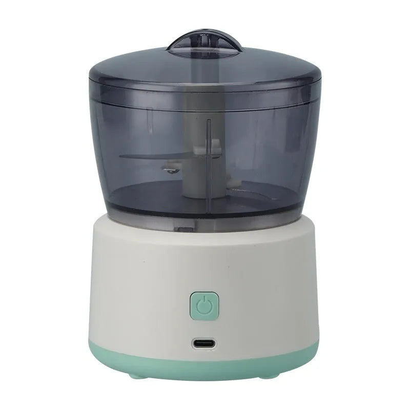 Mini electric meat grinder with transparent bowl and stainless steel blades on anti-slip pad