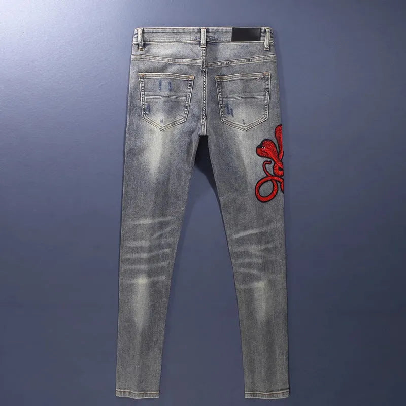 Old colour slim fit jeans with hole patches and embroidered detailing on worn cotton fabric