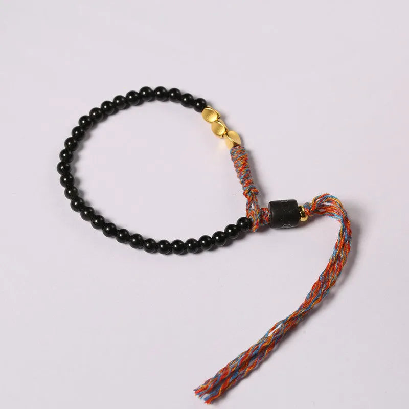 Slim obsidian-coloured hand-woven strap bracelet shown on a wrist.