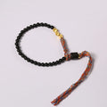 Slim obsidian-coloured hand-woven strap bracelet shown on a wrist.