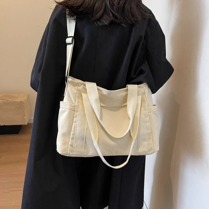 Women's solid colour canvas shoulder bag showing interior mobile phone compartment and exterior sandwich pocket